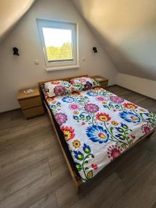a bedroom with a bed with a floral comforter and a window at Wrzosowisko Sominy in Sominy
