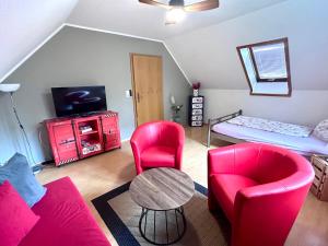 a living room with red chairs and a table and a bed at Ferien in Sachsen in Schmölln