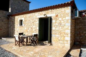 a table and chairs in front of a stone building at Olive Coast Houses in Kyparissia +14 photos
