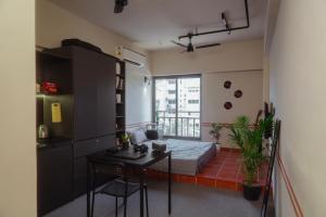 a room with a bed and a table and a kitchen at FLH Residences, Ambawadi in Ahmedabad