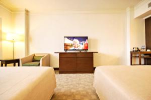 a hotel room with two beds and a flat screen tv at Lanna Palace 2004 in Chiang Mai