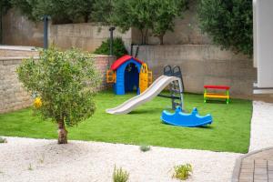 a backyard with a playground with a slide and a playset at Malo More Resort in Trogir