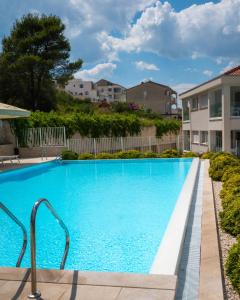 a large blue swimming pool in a yard with houses at Malo More Resort in Trogir