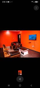 a living room with an orange wall and a couch at Mo Exortic Royale Services in Ikorodu +13 photos