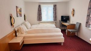 a hotel room with two beds and a desk at Hotel Heilquelle-Leukerbad-Therme in Leukerbad