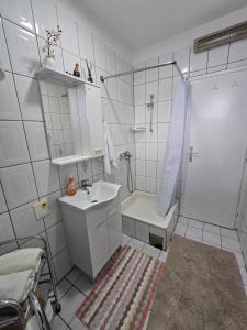 a white bathroom with a sink and a shower at Abrazo in Orašje
