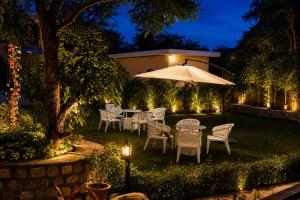 a patio with a table and chairs and an umbrella at Gauri Hayat Corbett Retreat in Rāmnagar