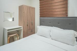 a bedroom with a white bed with a wooden headboard at Manzil Anilao B&B in Mabini