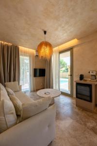 a living room with a white couch and a chandelier at Terra Elea Luxury Pool Suite Aura in Nikiti