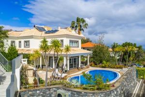 a large white house with a swimming pool in front of it at Villa Minimalista in Caniço