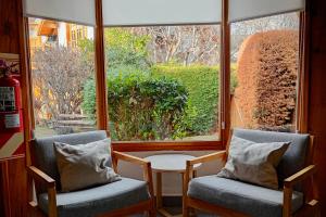 two chairs and a table in front of a window at Los Techos Apart in Esquel