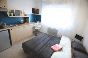 een slaapkamer met een bed en een keuken met een wastafel bij Résidence Les Portes d'Espagne in Perpignan