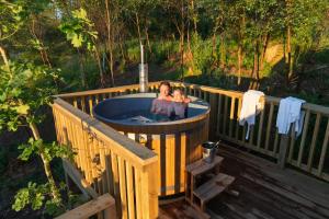 a woman and child sitting in a hot tub on a deck at Hazel Tree Yurt - Eavestone Lake in Grantley