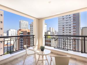 a balcony with a table and chairs and a view of the city at George V Casa Branca in São Paulo