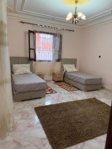 a bedroom with two beds and a chandelier at Samadis Home 3 in Larache