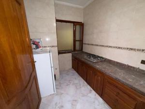 a kitchen with a white refrigerator and wooden cabinets at Samadis Home 3 in Larache +5 photos