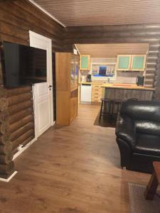 a living room with a black leather couch and a kitchen at Øse Camping in Gratangen