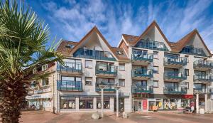 a building with a palm tree in front of it at Düne, App 7 in Duhnen