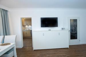 a living room with a flat screen tv on a white wall at Düne, App 7 in Duhnen