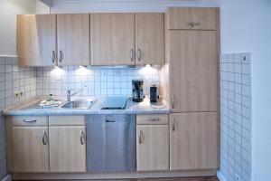 a kitchen with wooden cabinets and a sink at Düne, App 7 in Duhnen