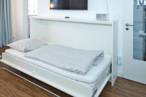 a white bed with a tv on top of it at Düne, App 7 in Duhnen