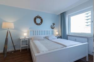 a white bedroom with a large bed and a window at Düne, App 7 in Duhnen +5 photos