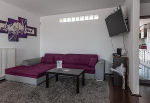 a living room with a purple couch and a table at Six Corners Mystic Corner City View Balcony Apartment in Pécs