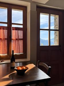 a dining room table with a bottle of wine and windows at Mountain hut 'la Fraccia' in Trasquera +26 photos