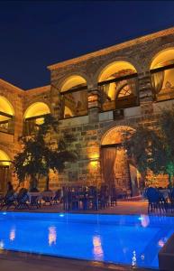 a large building with a swimming pool at night at Kervansaray Antique Hotel in Çeşme