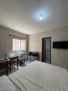 a bedroom with a bed and a desk and a television at Residencial Sol - Cidade alta in Natal