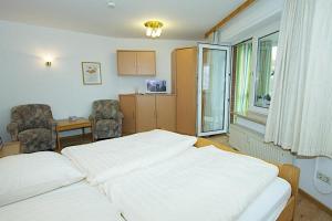 a bedroom with a white bed and a table and chairs at Düne, App 12 in Duhnen