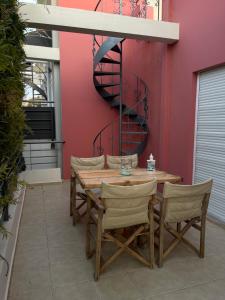 a wooden table with chairs and a spiral staircase at Cozy beach apartment in Saronida in Saronida