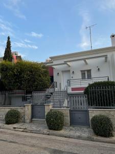 a white house with a gate in front of it at Cozy beach apartment in Saronida in Saronida