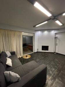 a living room with a couch and a flat screen tv at Cozy beach apartment in Saronida in Saronida