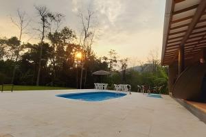 a pool with chairs and a table and the sunset at Cabana surucuã in Três Coroas
