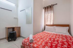 a bedroom with a bed with a red blanket and a window at Oreo rooms in Kozhikode