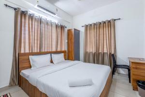 a bedroom with a large bed with a desk and curtains at Oreo rooms in Kozhikode