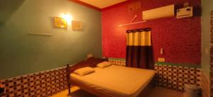 a bedroom with a bed in a room with red walls at Mangrove Pitta - Bhitarkanika in Kendrāparha