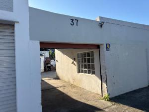 a white building with a garage door with a window at Aiden guest house in Gqeberha