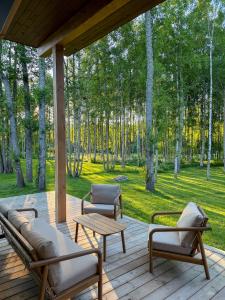 a porch with a couch and chairs on a wooden deck at Jõelähtme Golf Villa with Sauna and Terrace Grill - near EGCC Golf Course in Manniva