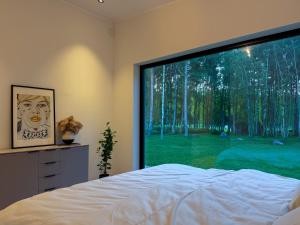 a bedroom with a large window looking out at a green yard at Jõelähtme Golf Villa with Sauna and Terrace Grill - near EGCC Golf Course in Manniva