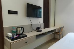 a hotel room with a desk with a television on it at 7 Pearls in Gajendragarh +16 photos
