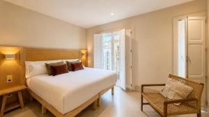 a bedroom with a large white bed and a chair at Cosy Rooms Tapinería in Valencia