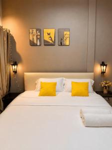 a bedroom with a large white bed with yellow pillows at Beyond Stay Thong Lor 11 in Bangkok +21 photos