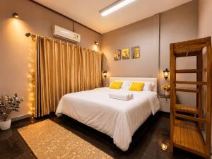 a bedroom with a large white bed with yellow pillows at Beyond Stay Thong Lor 11 in Bangkok