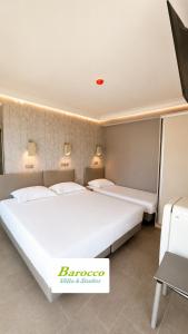 two beds in a room with two lamps on the wall at Barocco Villa & Studios in Potamiá