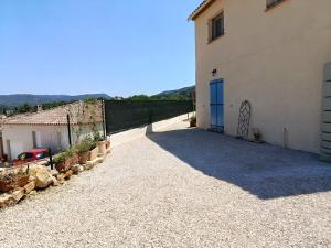 a driveway leading to a building with a blue door at Studio Jasmin in Le Beausset