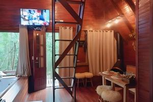 a room with a ladder and a table and a television at Cabana Andorinha in Três Coroas
