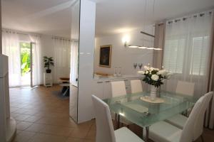 a dining room with a glass table and white chairs at Elegant Villa Hariz near Poreč - Fully AC & Large Pool in Gedići