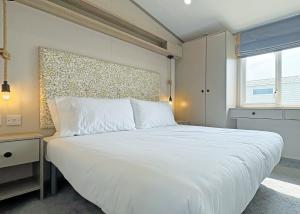a bedroom with a large white bed and a window at Golden Anchor Caravan Park in Chapel Saint Leonards